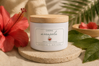 Amapola candle by Chispas with a wooden lid, styled with hibiscus flower and green leaves on a warm natural surface.