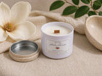 Pétalos Blancos candle by Chispas with wooden lid, styled with magnolia flower and soft neutral textures in a clean, airy setting.