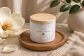 Pétalos Blancos candle by Chispas with wooden lid, styled with magnolia flower and soft natural elements on a clean, minimal surface.