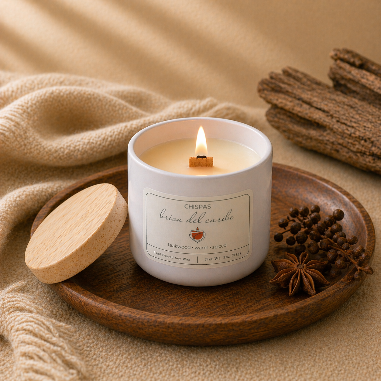 Hand-poured Brisa del Caribe candle by Chispas with a wooden wick burning on a tray, surrounded by warm spiced elements.